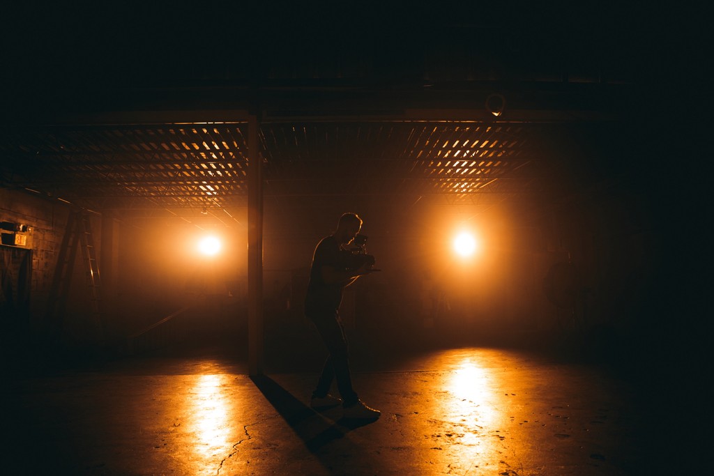 A camera operator working in a lit warehouse space